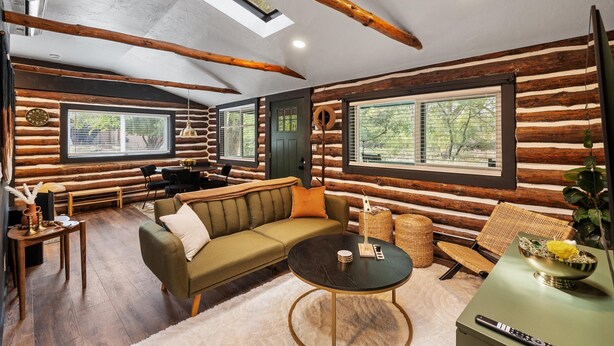 A log cabin interior with a sofa, coffee table, and dining area. - The Prescott Granite Dell's Getaway! (Prescott)