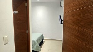 A room with a bed, a wooden door with a number, a wall-mounted TV, and a door with a 'Fumar' sign. - Villa Leo Beautiful room with shared kitchenette, in the heart of Cancun (Cancun)