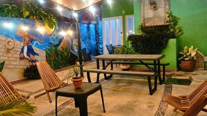 An outdoor patio with wooden lounge chairs, a picnic table, and a mural on the wall. - Villa Leo Beautiful room with shared kitchenette, in the heart of Cancun (Cancun)