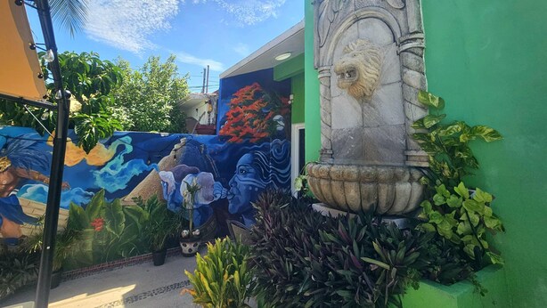 A building with a green wall, a stone lion head sculpture, and a mural with blue and red colors. - Villa Leo Beautiful room with shared kitchenette, in the heart of Cancun (Cancun)