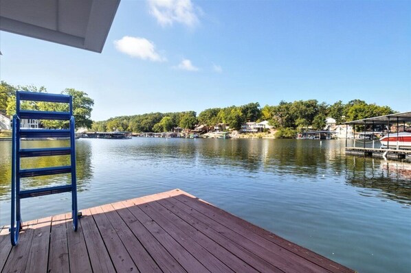 A wooden dock extending into a calm lake with a clear sky.