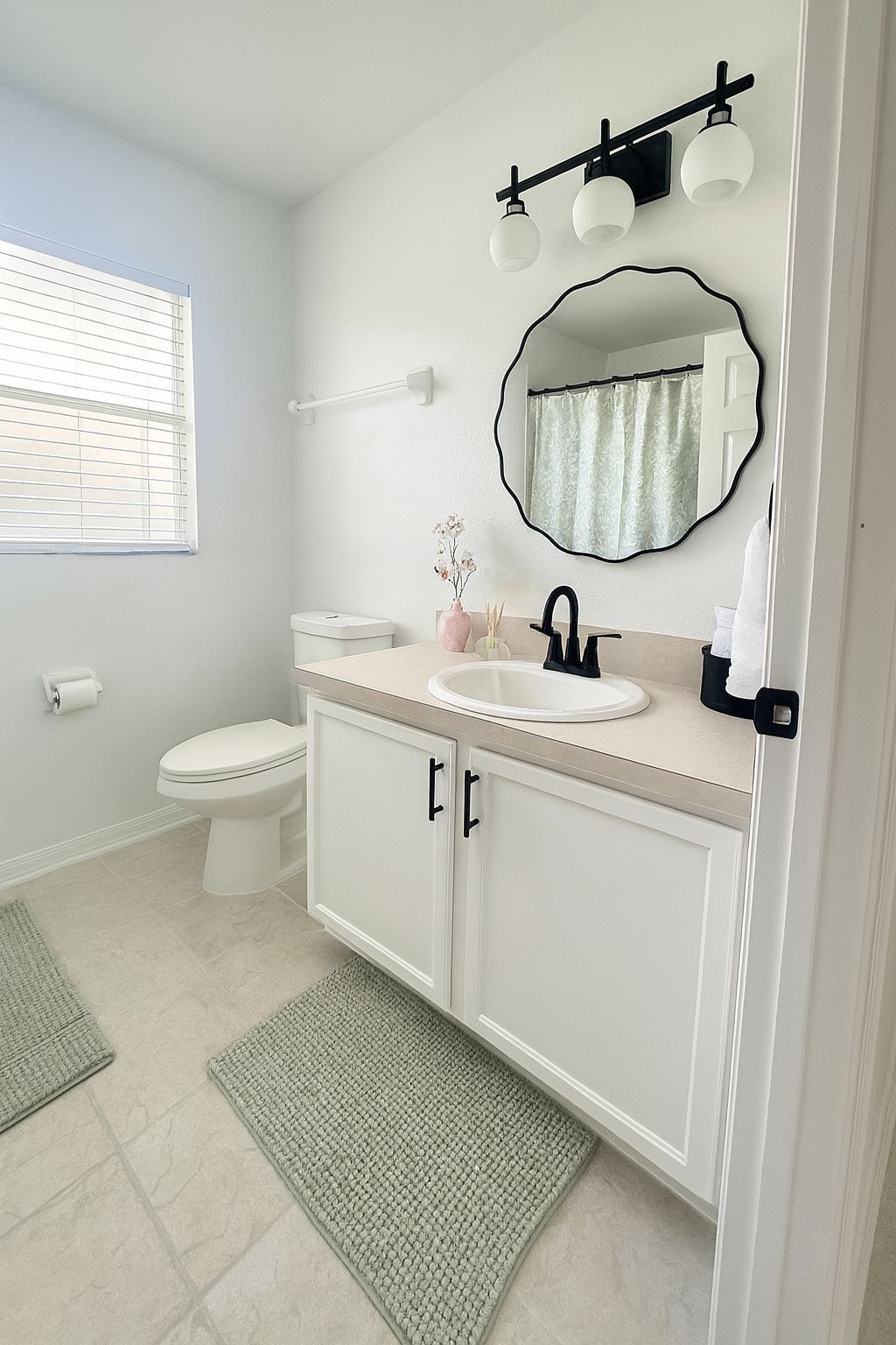 A bathroom with a toilet, sink, mirror, and towel rack.