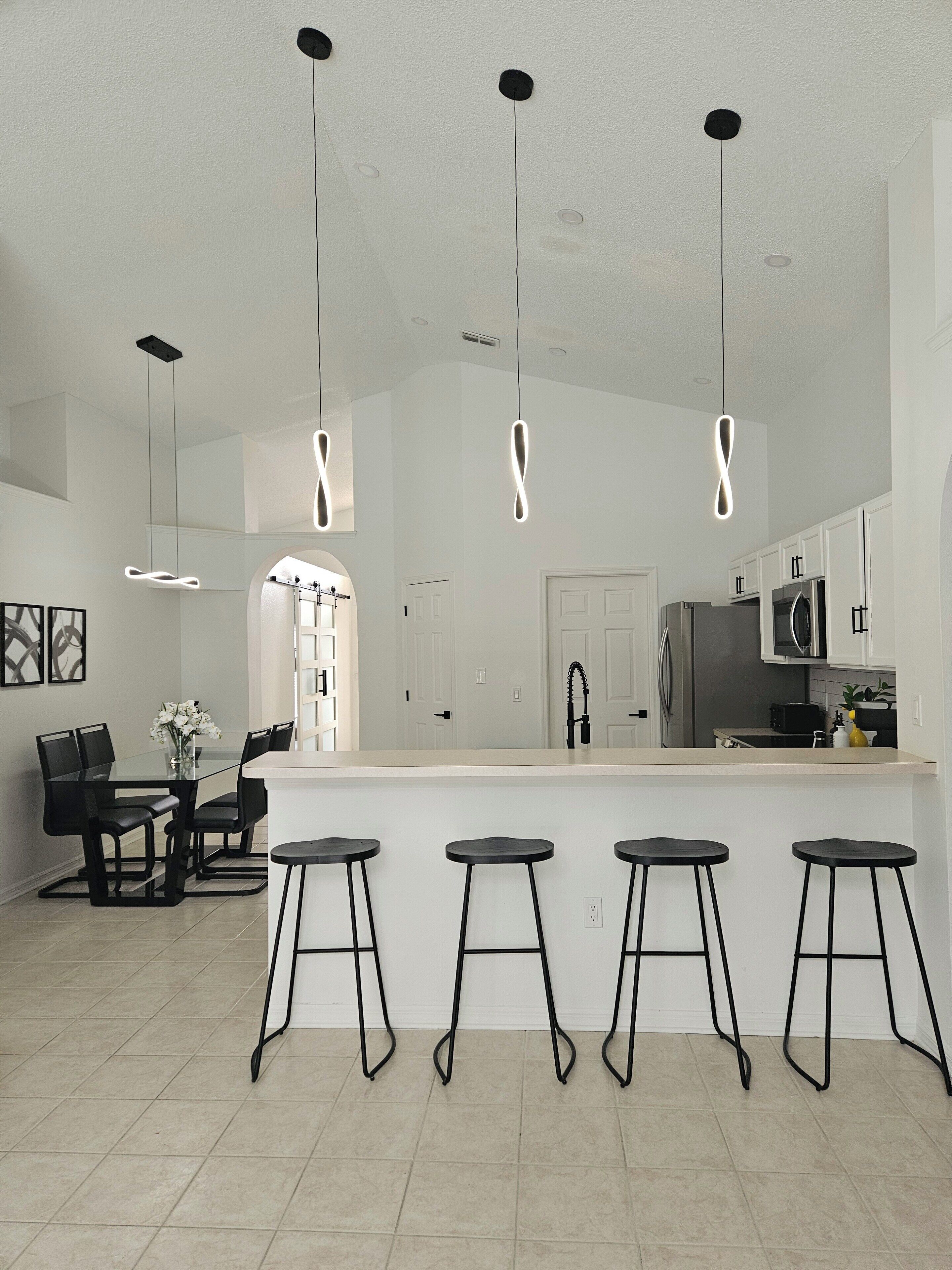 Een moderne keuken met een centraal eiland, barstoelen en hanglampen.