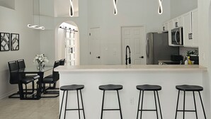 Una cocina moderna con una isla central, taburetes de bar e iluminación colgante.
