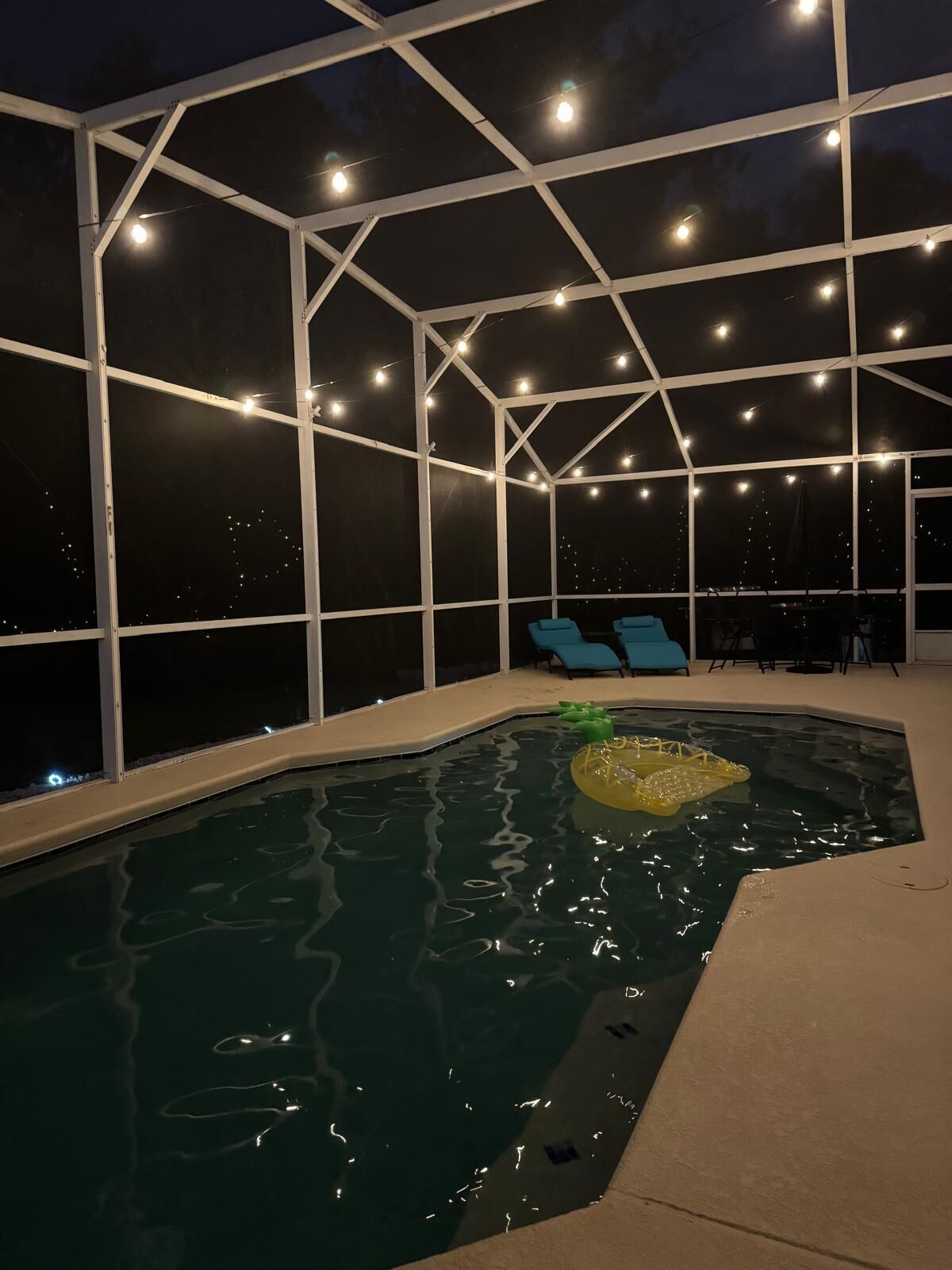 Een zwembadgedeelte met heldere glazen wanden, lichtjes en blauwe stoelen.