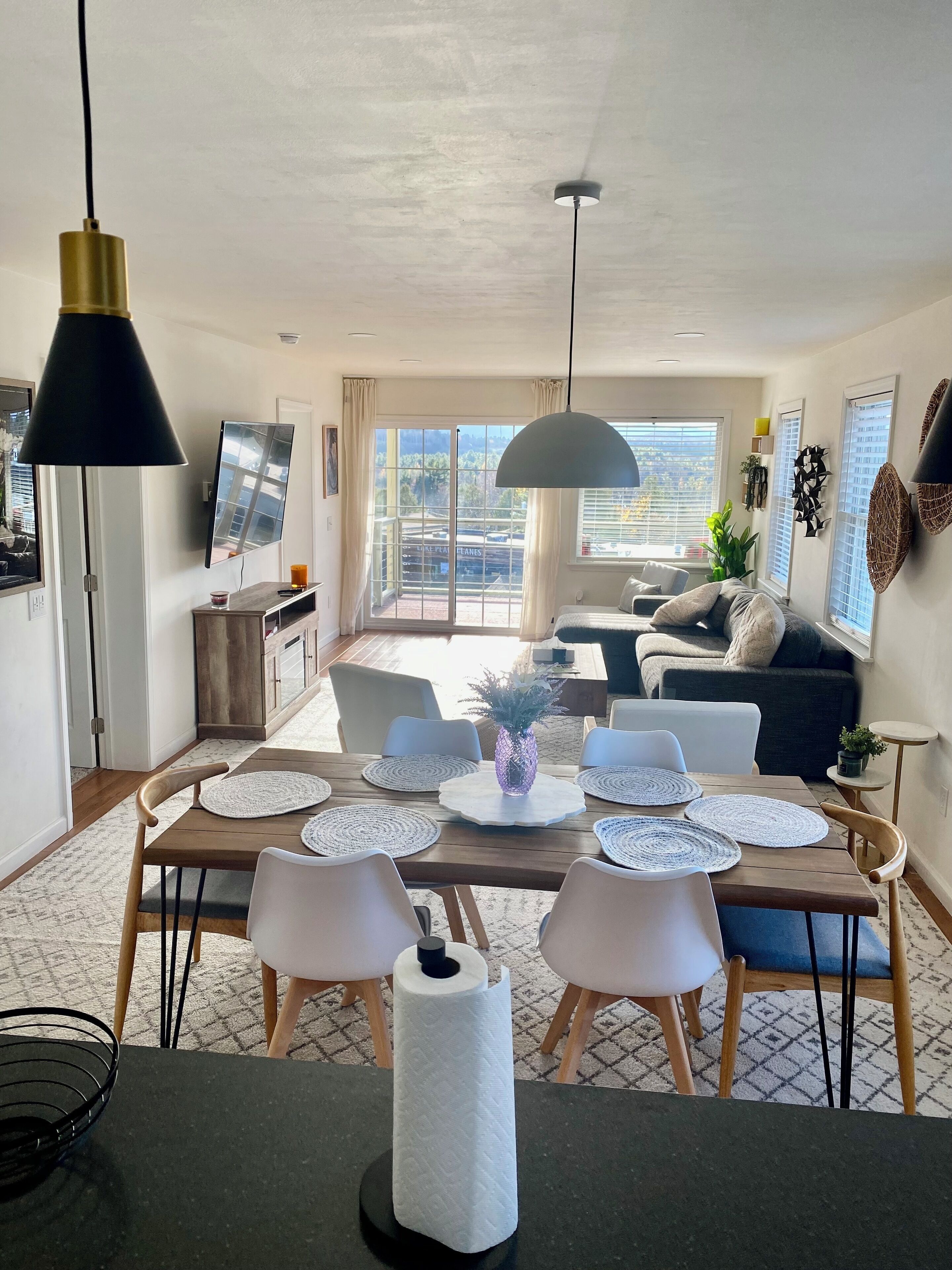 A modern living room with a dining area, large windows, and a view of the city.
