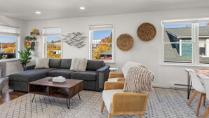 A modern living room with a sectional sofa, a coffee table, and a dining area with a table and chairs. - Amazing Mountain Views  (Lake Placid)