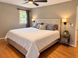 A bedroom with a bed, a ceiling fan, a nightstand with a lamp, and a window with curtains. - Adventure Hub/Near Pisgah National Forest, SierraNevada, Restaurants & Breweries (Mills River)