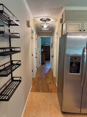 A kitchen with a stainless steel refrigerator, wooden flooring, and black metal shelves on the wall. - Adventure Hub/Near Pisgah National Forest, SierraNevada, Restaurants & Breweries (Mills River)