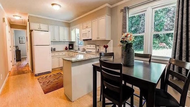 A kitchen with white cabinets, a central island, and a dining area with a table and chairs.