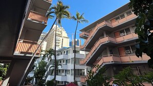 A courtyard with multiple-story buildings, palm trees, and outdoor seating areas. - Relax in Style: Waikīkī Condo w/ Lanai (Honolulu)