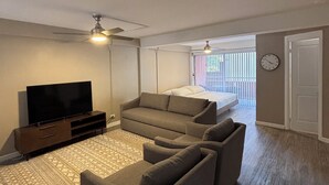 A living room with a flat-screen TV, two sofas, a ceiling fan, and a patterned rug. - Relax in Style: Waikīkī Condo w/ Lanai (Honolulu)