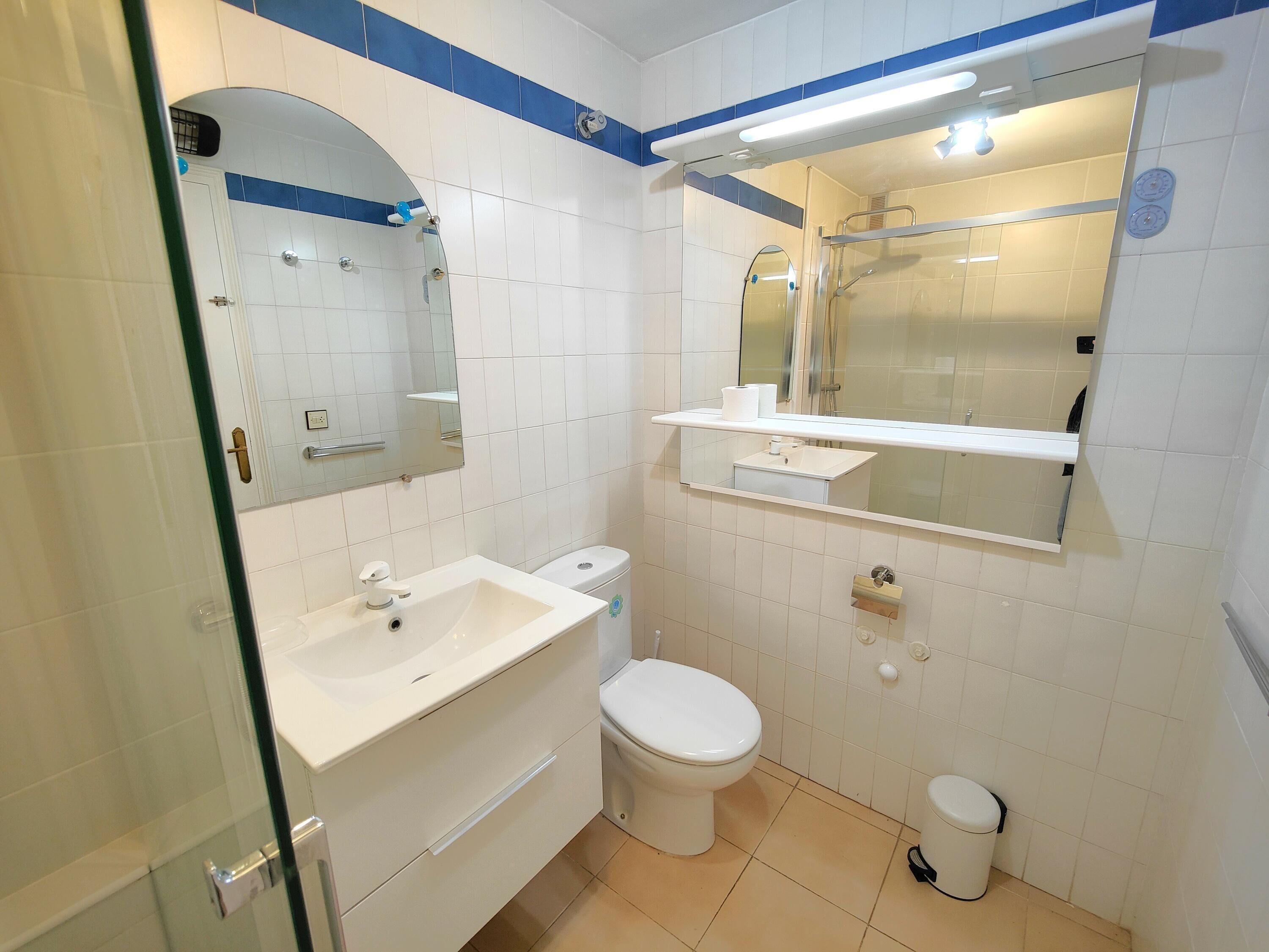 A bathroom with a white sink, toilet, and bidet, a mirror above the sink, and a shower area with a glass door.