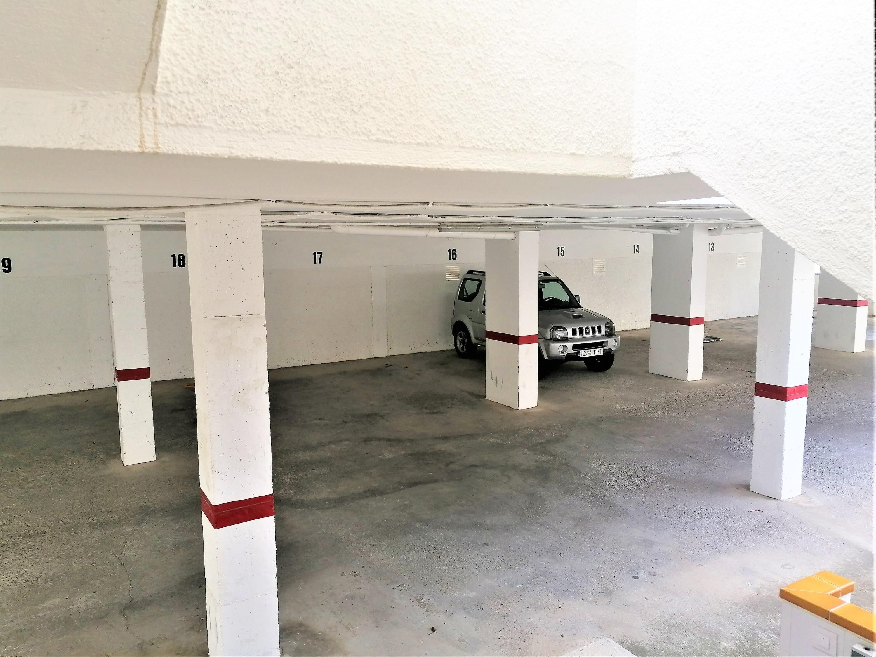 Un aparcamiento con plazas numeradas y un coche estacionado en la plaza número 17.