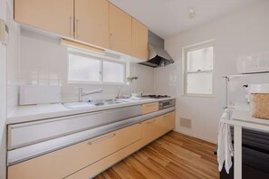 A modern kitchen with a stainless steel countertop, beige cabinets, and a built-in oven. - Home in Sangenjaya, Tokyo | 2 Stops to Shibuya (世田谷区)
