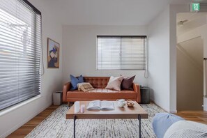 A modern living room with a leather sofa, a coffee table with books and a teapot, and a framed picture on the wall. - Home in Sangenjaya, Tokyo | 2 Stops to Shibuya (世田谷区)