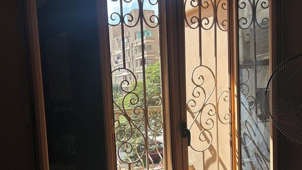 Une pièce dotée d’une porte-fenêtre coulissante donnant sur un balcon agrémenté d’une grille en métal.