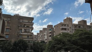 Un quartier résidentiel avec des immeubles à plusieurs étages, des voitures garées et des arbres.