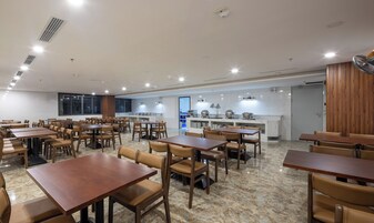 Un comedor amplio con varias mesas y sillas, una cocina con encimeras de mármol y grandes ventanales que ofrecen luz natural.