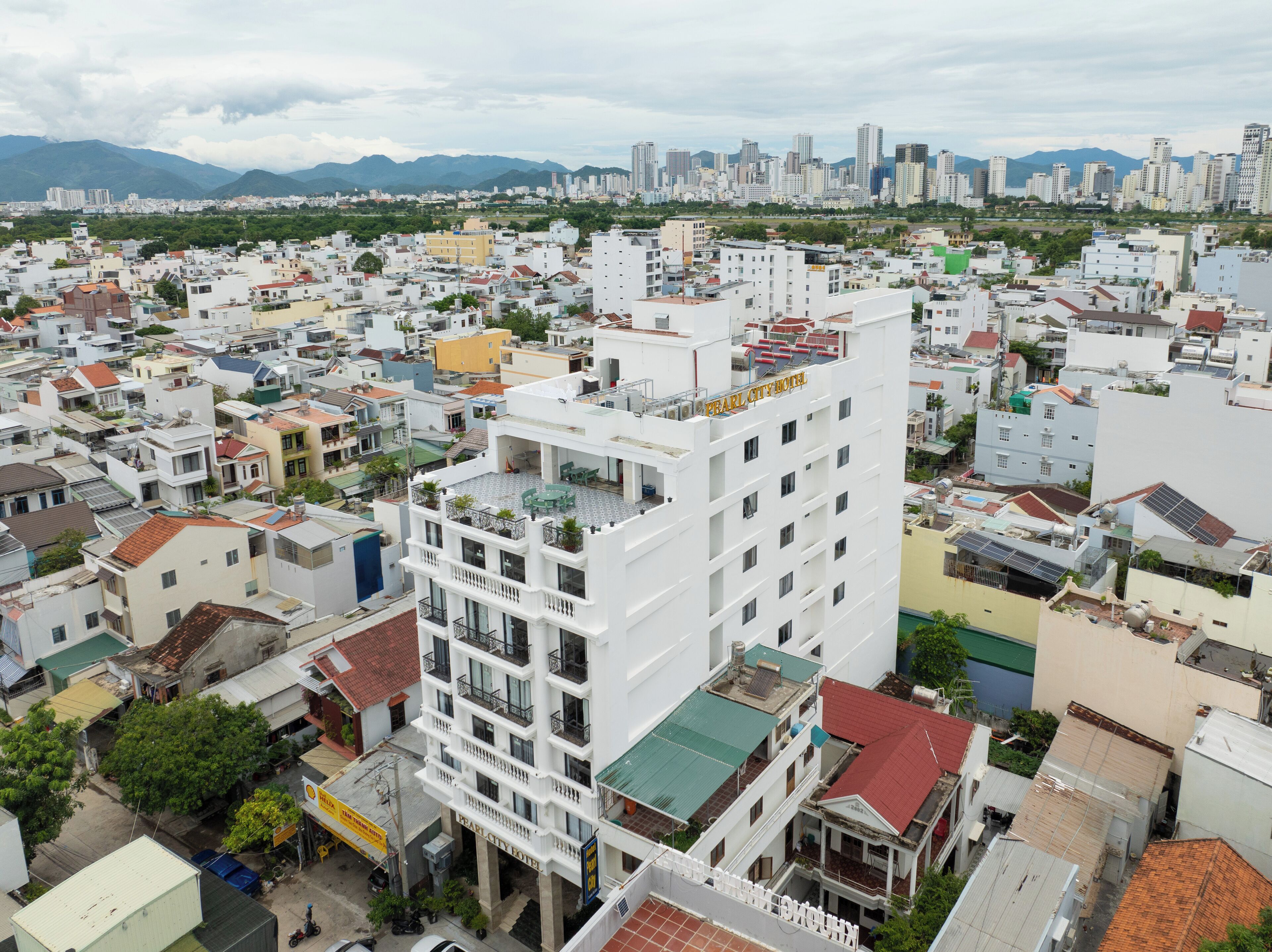 Un hôtel à plusieurs étages, doté de balcons, situé dans un quartier urbain dense et entouré de différents bâtiments.