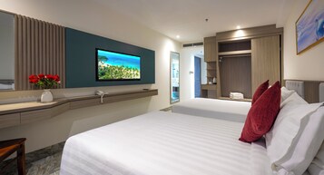 Una habitación de hotel con una cama, un escritorio con computadora, un televisor y un armario.