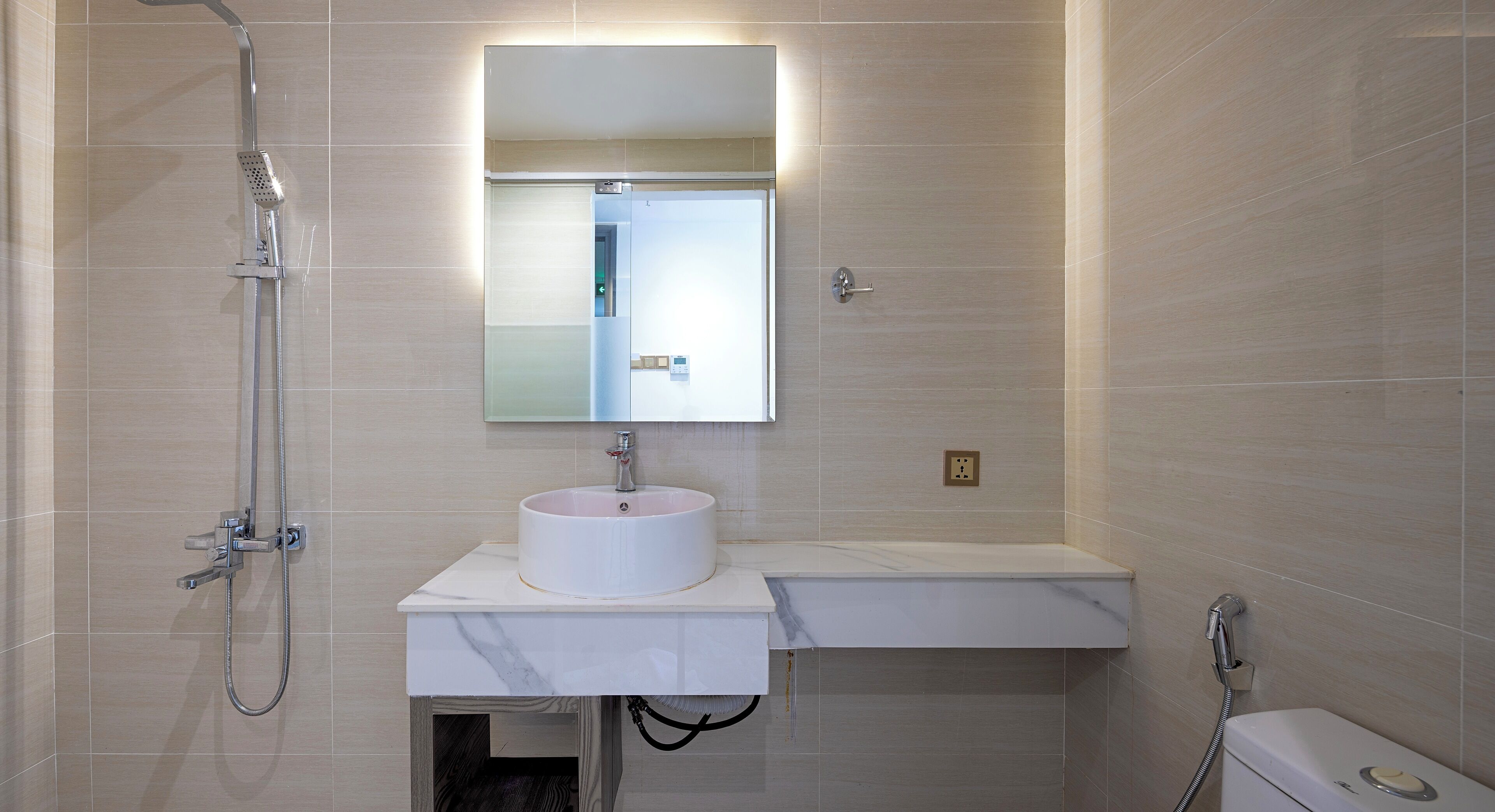 Une salle de bain moderne avec un lavabo blanc, un miroir et une douche.