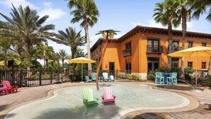 A swimming pool with lounge chairs, palm trees, and a building with balconies. - Paseo Grande 3 Bedroom Resort Oasis (Fort Myers)