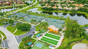 An aerial view of a residential area with multiple tennis courts, a swimming pool, and a small building. - Paseo Grande 3 Bedroom Resort Oasis (Fort Myers)