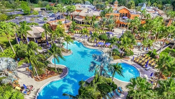 A resort with a large central pool surrounded by palm trees and sun loungers. - Paseo Grande 3 Bedroom Resort Oasis (Fort Myers)
