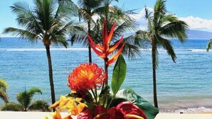 Blick auf einen tropischen Strand mit Palmen und einer Blumenkomposition.