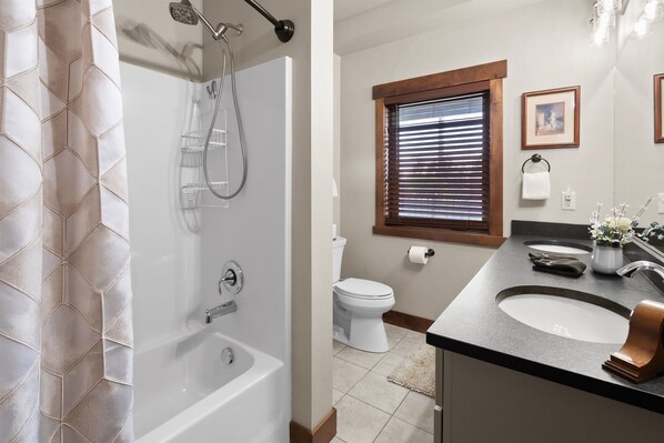 Une salle de bain moderne équipée d’une baignoire, d’une douche, de toilettes et d’un meuble-lavabo avec un évier et un miroir.