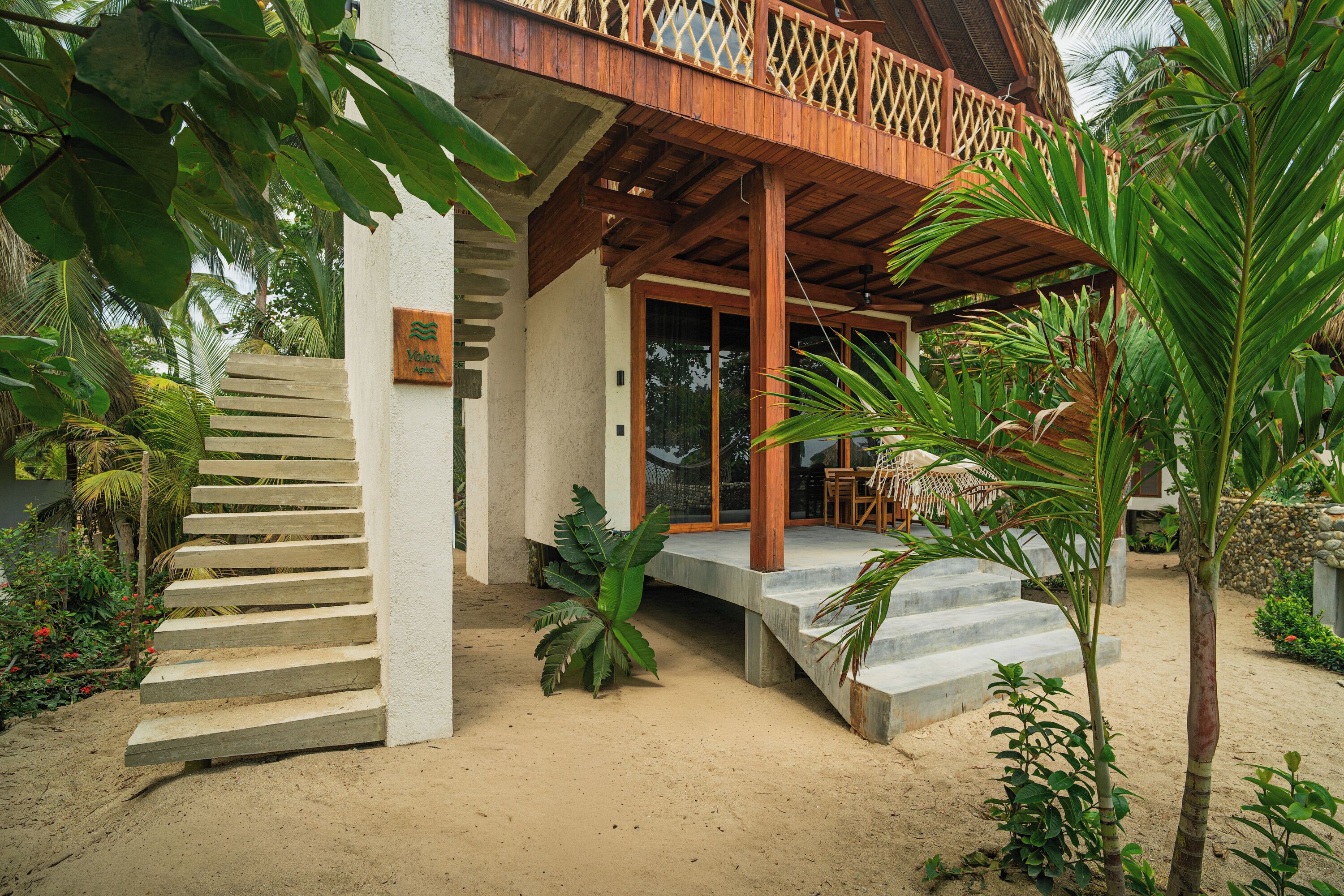 A wooden balcony with a lattice railing, a concrete staircase leading to a door, and a sign that reads "Yukon Resort".