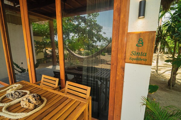 A wooden table with a rope and a wooden chair, a hammock, and a sign with the number 8 and the name 'Sinta Equilibrio'. - Casa Iwana Tayrona (Santa Marta)