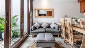 Un salon moderne avec un canapé gris, une table à manger en bois et un grand miroir au mur.