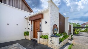 Une maison moderne avec une façade en pierre, une porte en bois et un petit jardin agrémenté de plantes en pot.