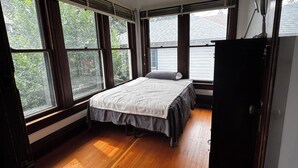 Ein Schlafzimmer mit Bett, großen Fenstern und Holzboden.