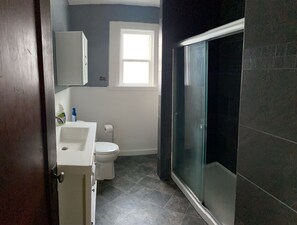 Ein Badezimmer mit Toilette, Waschbecken und Duschkabine aus Glas.