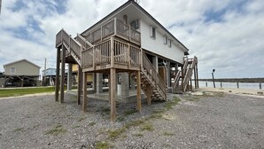 Een houten huis met een balkon en een trap naar de begane grond.