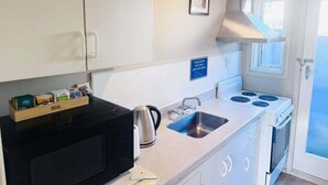 Une cuisine compacte équipée d’un four à micro-ondes, d’une bouilloire, d’un évier et d’une cuisinière.