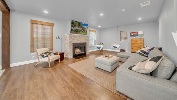 A modern living room with a fireplace, a sofa set, and a large window with blinds.
