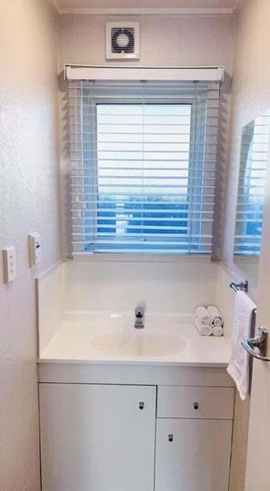 Un baño pequeño con ventana, lavamanos y espejo.