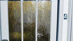 Una puerta blanca con tres paneles de vidrio y un pequeño ventanal encima.