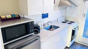 Una kitchenette compacta equipada con microondas, tostadora, pileta y cocina.