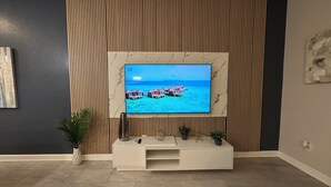 Un salon avec un téléviseur à écran plat fixé au mur, lequel est décoré d’un motif à rayures.