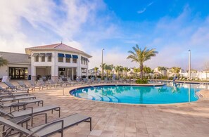A swimming pool with lounge chairs and a building with a red roof. - 4BR/3BA Townhouse w/ Private Pool in Storey Lake (Kissimmee)