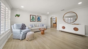 A modern living room with a light-colored sofa, a small round coffee table, and a white cabinet with a mirror. - Tropical Retreat • Pool • 1.5 miles to Beach (Hobe Sound)