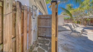 A wooden gate leading to a patio area with stone flooring and a palm tree in the background. - Tropical Retreat • Pool • 1.5 miles to Beach (Hobe Sound)