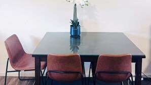 Une table avec une horloge, deux chaises et une plante en pot.
