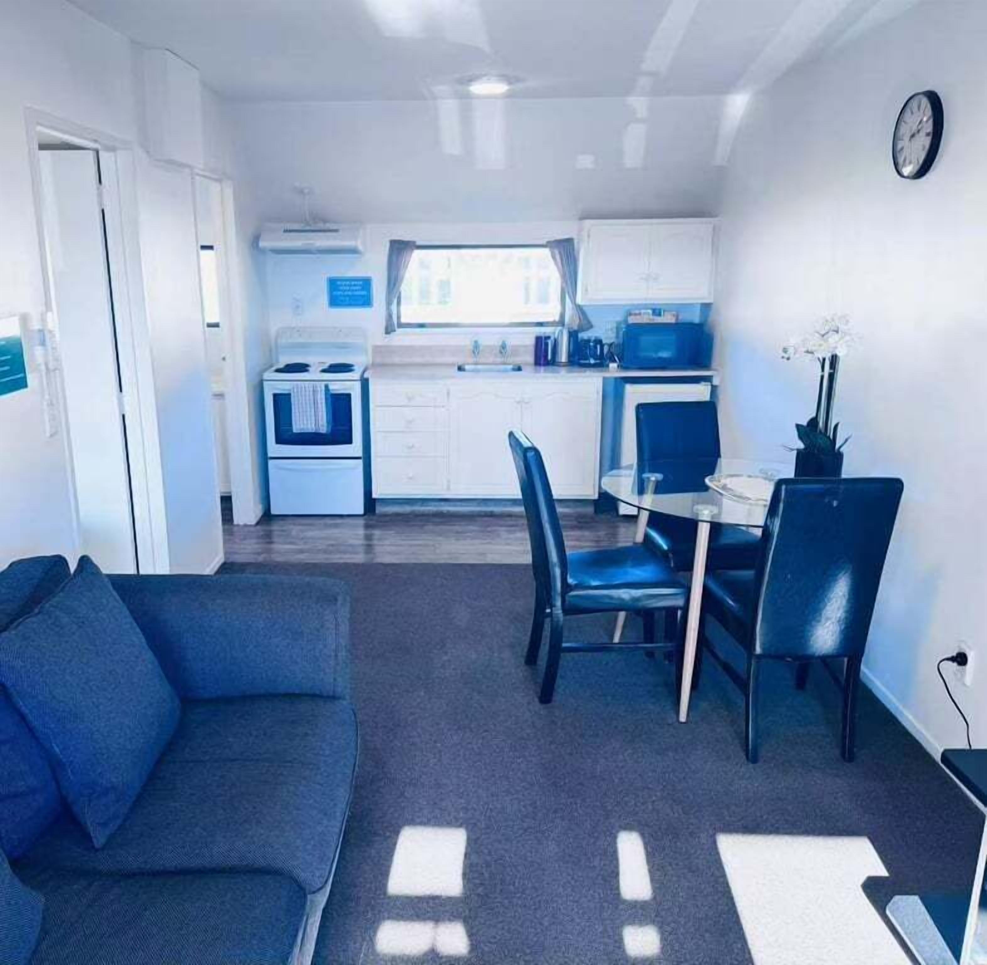 A compact living space with a kitchenette, a dining area with a table and chairs, and a sofa.