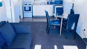 A compact living space with a kitchenette, a dining area with a table and chairs, and a sofa.